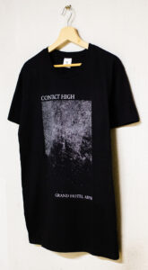 A black shirt with a white print of the album cover art. It reads "Contact High" and "Grand Budapest Hotel" in between those texts is an abstract gradient of points. It is seen from a slight angle.